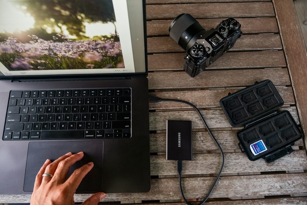 Laptop, camera, and memory card reader on wooden table